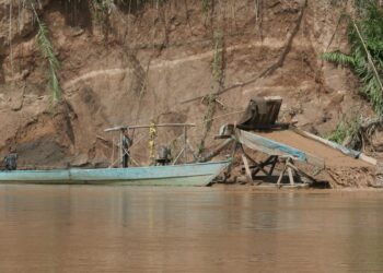 Draga artesanal de succión para extraer oro junto a una embarcación en la orilla del río Madre de Dios, en la Amazonía peruana.