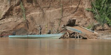 Draga artesanal de succión para extraer oro junto a una embarcación en la orilla del río Madre de Dios, en la Amazonía peruana.