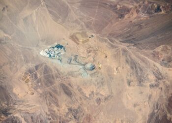 Vista satelital del desierto de Atacama en tonos ocres, con rajos abiertos, depósitos y caminos mineros del distrito Centinela en el centro de la imagen.