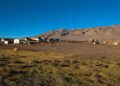 Pequeño poblado de casas bajas en la Puna salteña, con un terreno de pasto seco en primer plano y cerros áridos de tonos ocres bajo un cielo azul despejado.